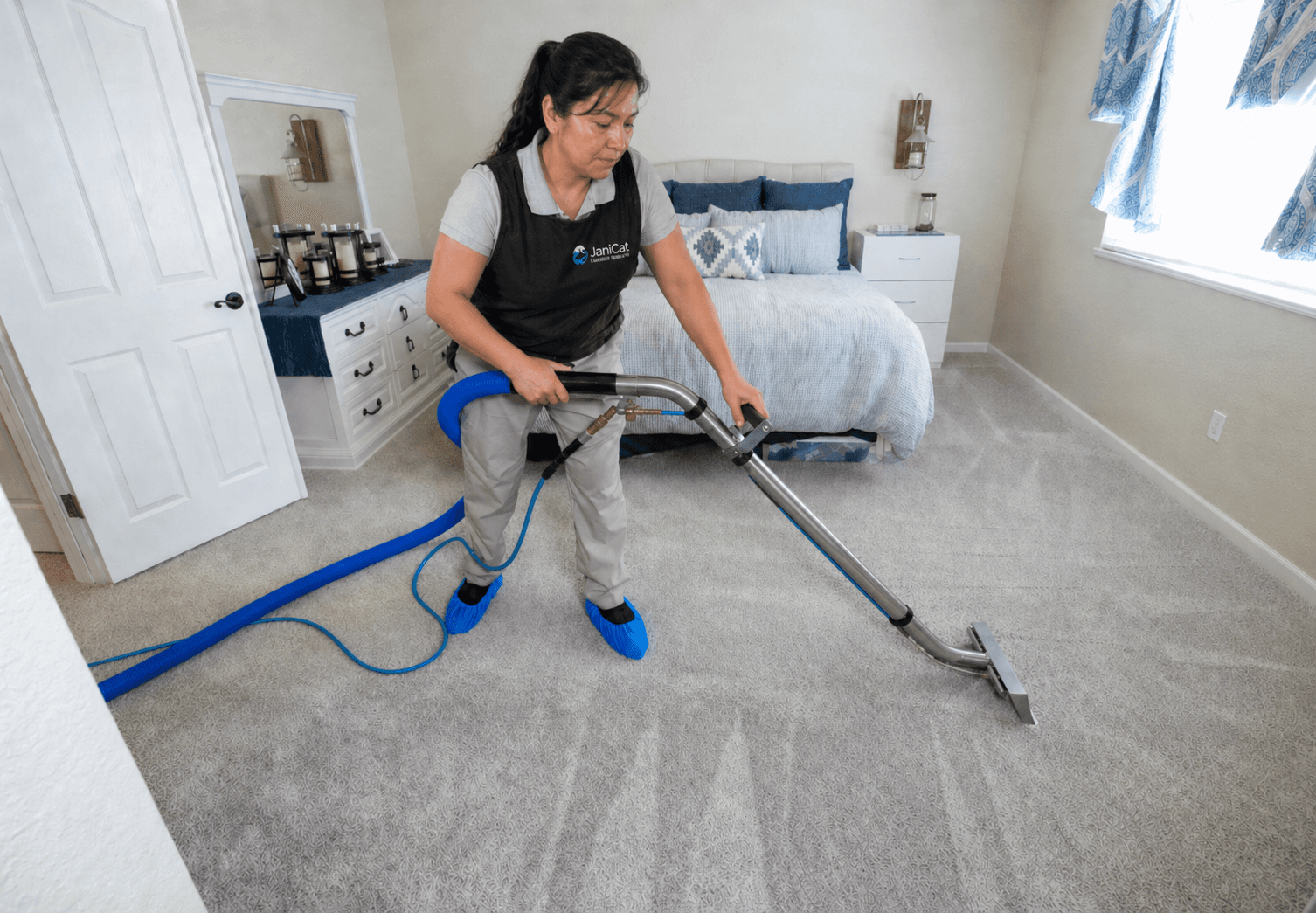Janicat team member deep-cleaning a bedroom carpet